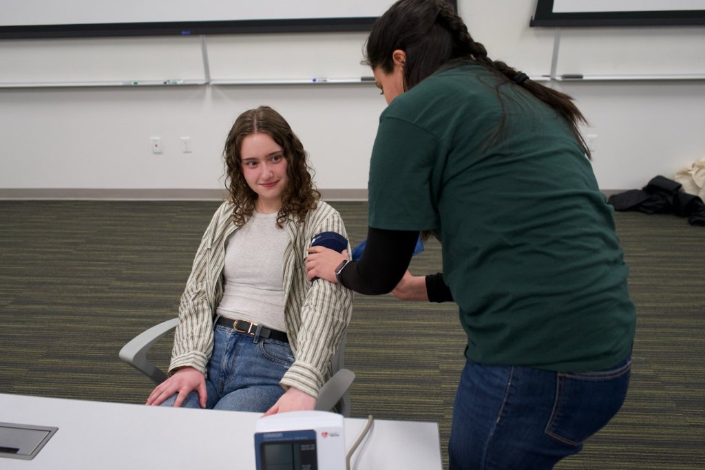 A team member fits a blood pressure cuff on a volunteer's arm during the Avenues 2025 demonstration.