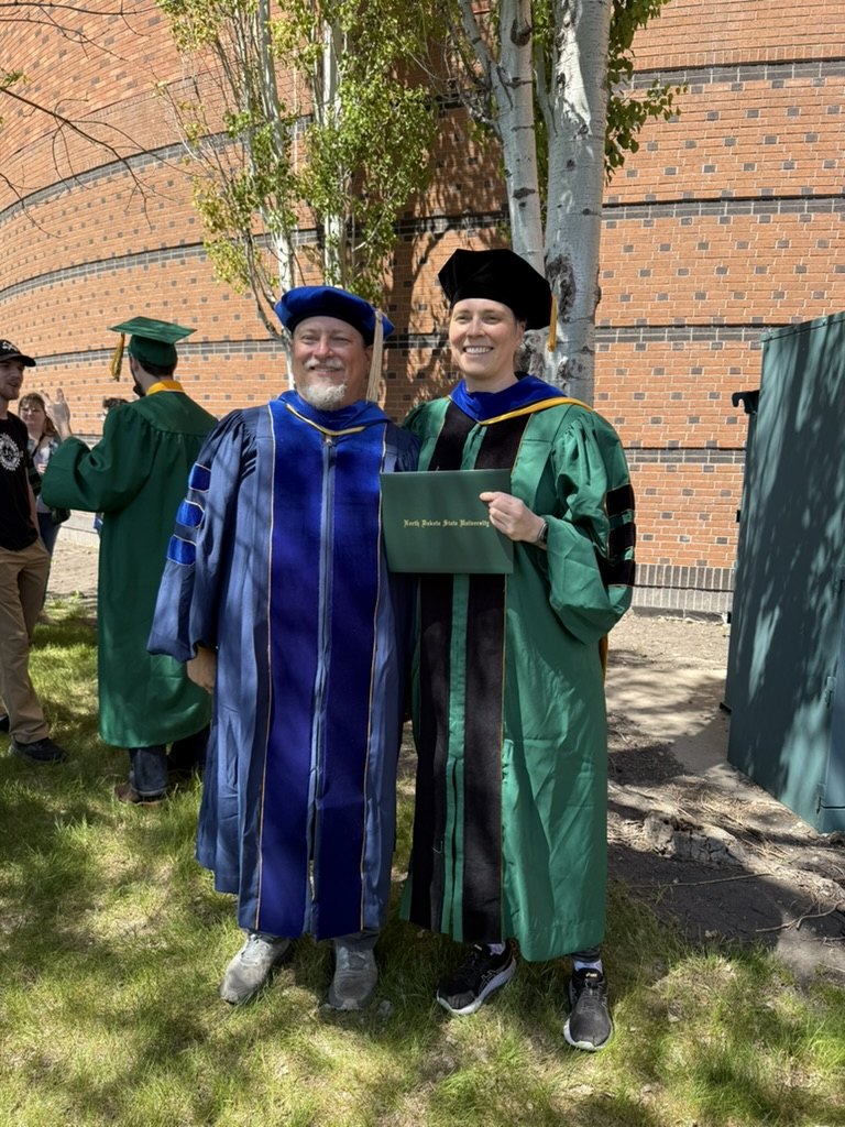 Dr. Anna Strahm holding her diploma beside Clayton Hilmert at NDSU commencement