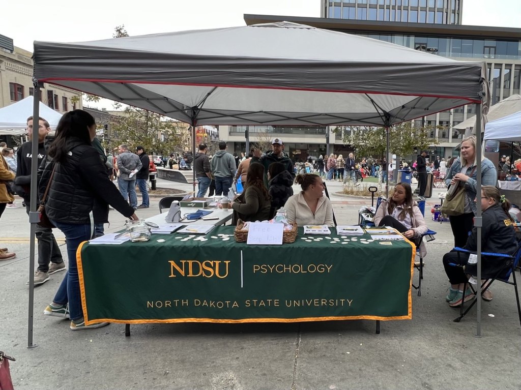NDSU Psychology outreach tent at the Red River Market, with free sleep kits and blood pressure checks