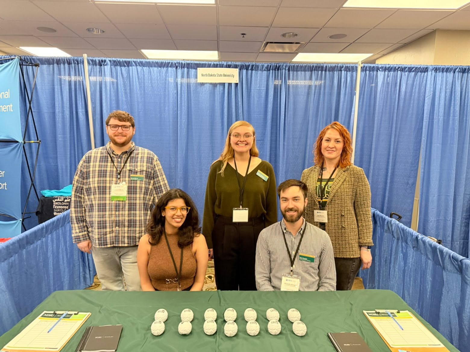 Five NDSU Psychology representatives at the department's exhibitor booth at the 2026 Midwestern Psychological Association meeting