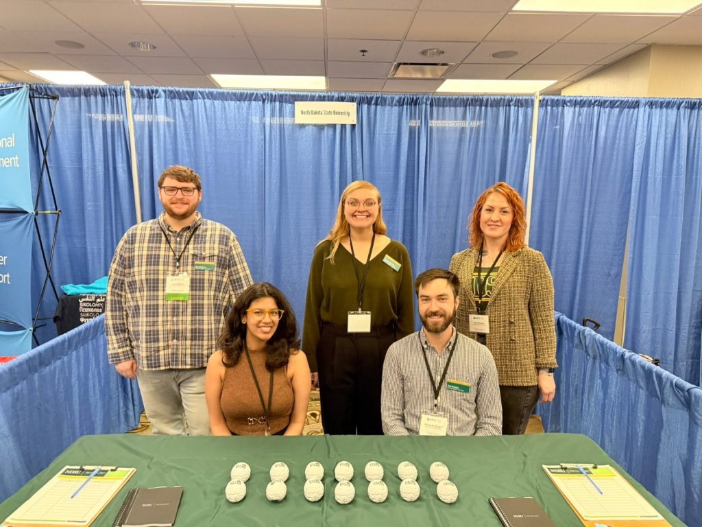 Five NDSU Psychology representatives at the department's exhibitor booth at the 2026 Midwestern Psychological Association meeting