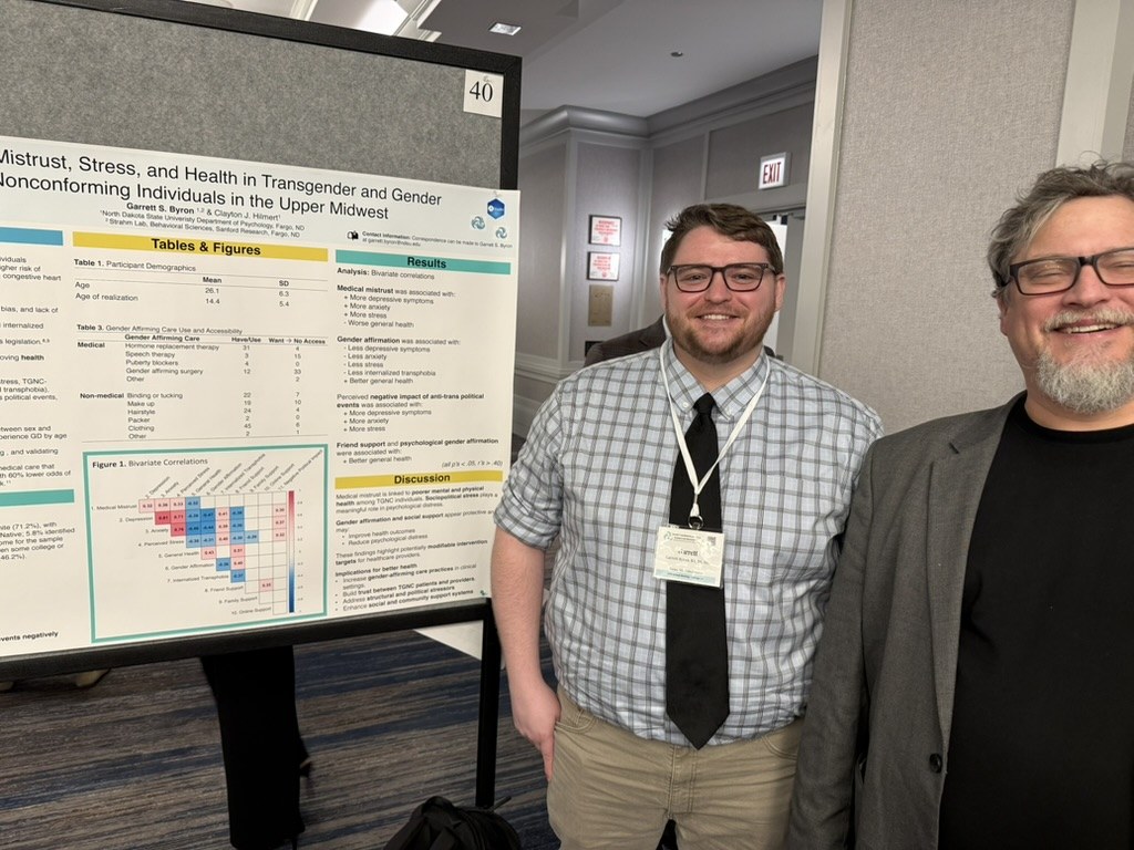 Garrett Byron and Clayton Hilmert with Garrett's citation poster on medical mistrust at SBSM 2026