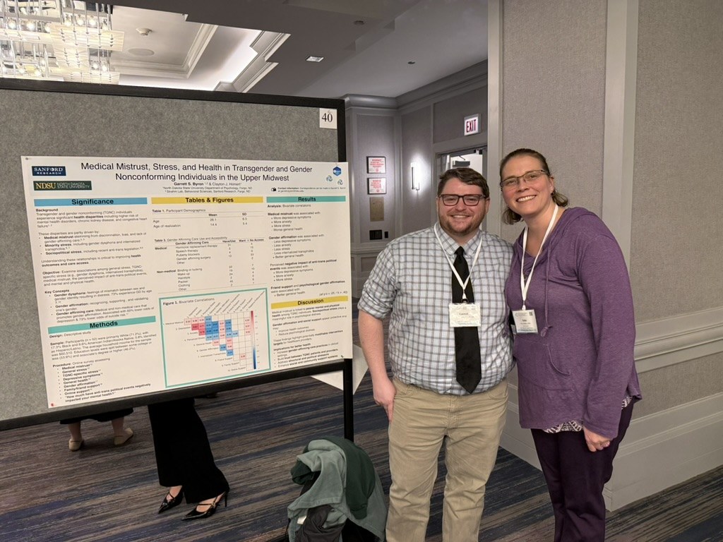 Garrett Byron and Dr. Anna Strahm beside Garrett's poster on medical mistrust, stress, and health at SBSM 2026