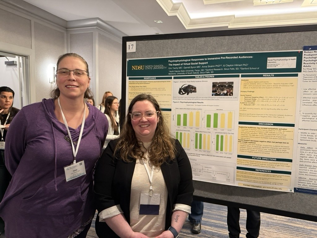 Dr. Anna Strahm and Erin Twohy beside Erin's citation poster on virtual social support at SBSM 2026